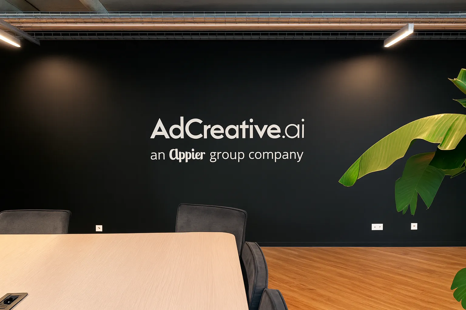 Logo AdCreative.ai en lettres blanches en relief sur un mur noir de salle de réunion