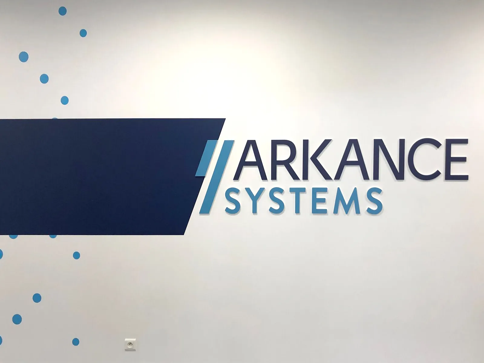 Logo Arkance Systems en lettres PVC bleues sur un mur blanc