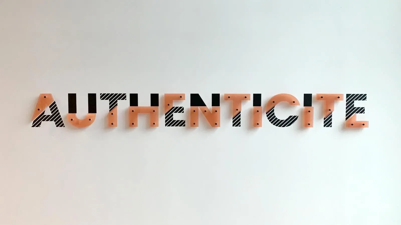 Mot Authenticité en lettres PMMA imprimées de rayures noires et orange