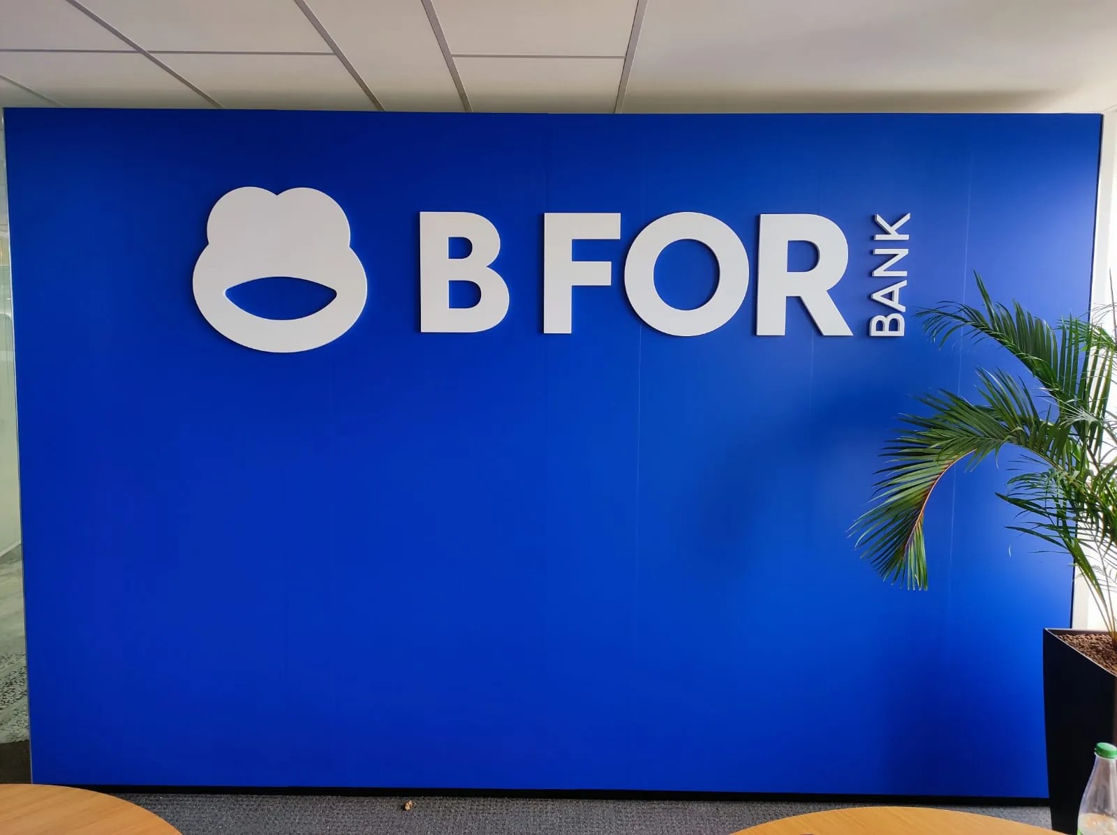 Logo B FOR BANK en grandes lettres blanches en relief sur un mur bleu vif