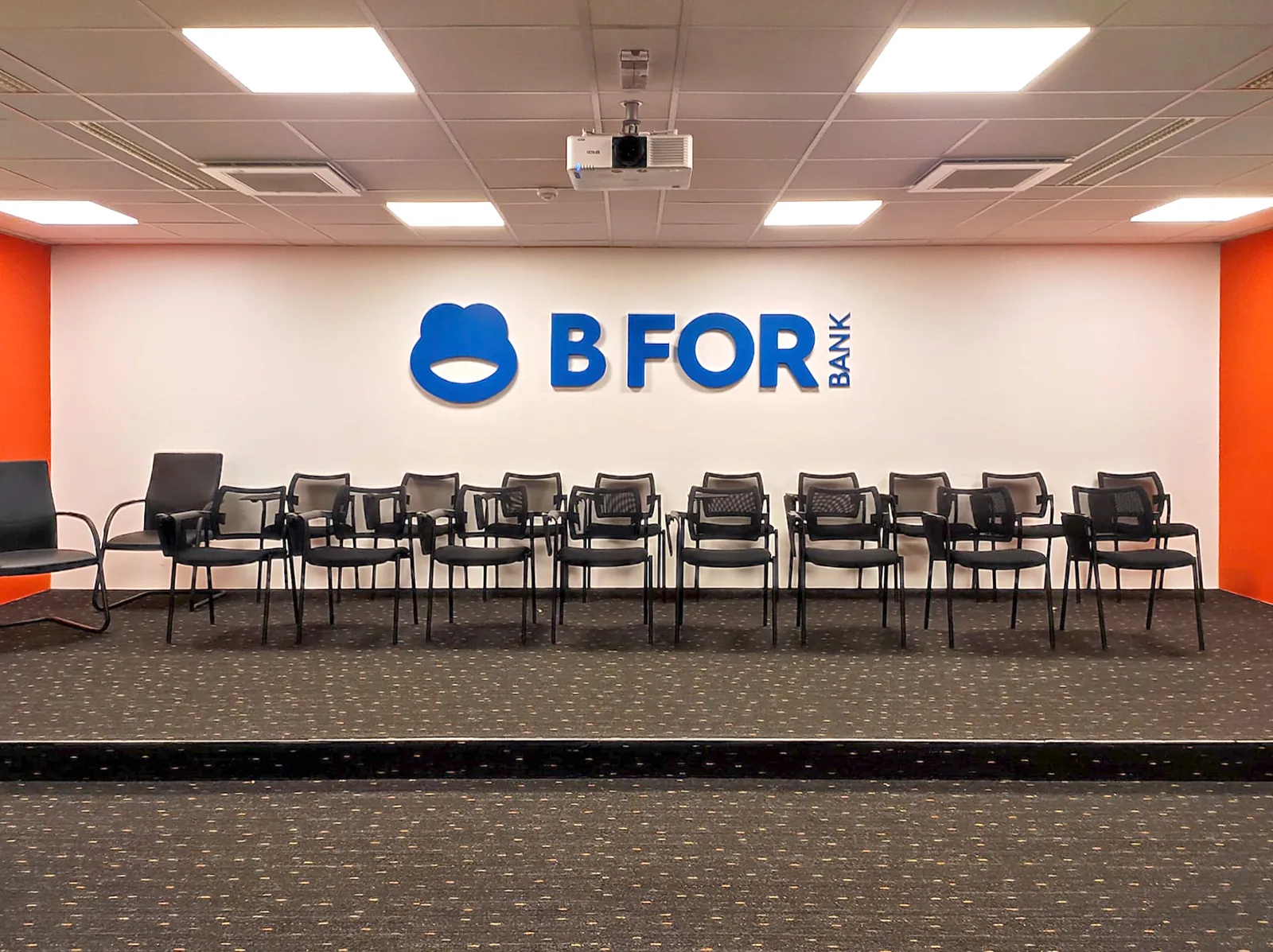 Logo BforBank en lettres bleues en relief au fond d'une salle de conférence
