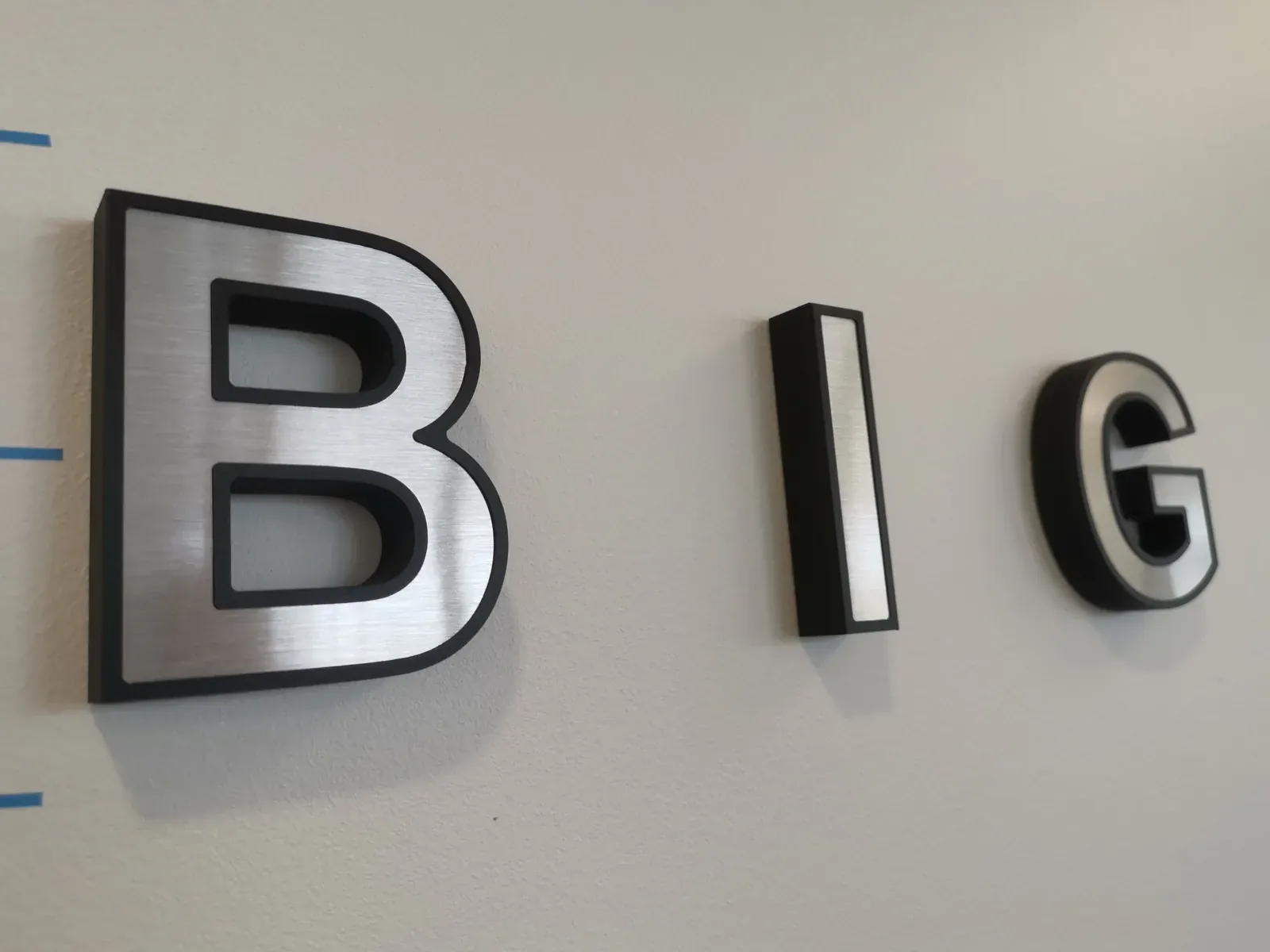 Lettre B de BIG en relief, face argentée et chants noirs, vue rapprochée