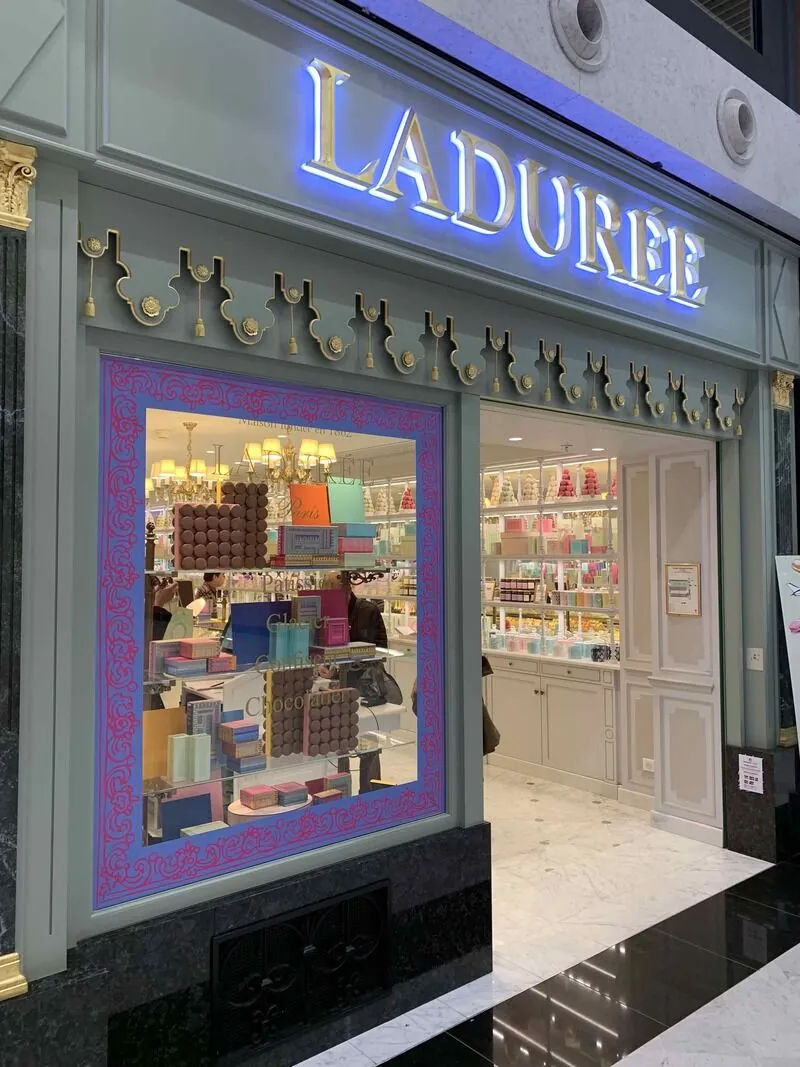 Enseigne Ladurée en lettres rétroéclairées sur une façade de boutique vert d'eau