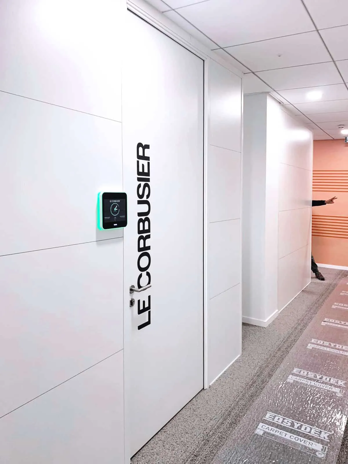 Nom de salle Le Corbusier en lettres noires posées à la verticale sur une porte blanche
