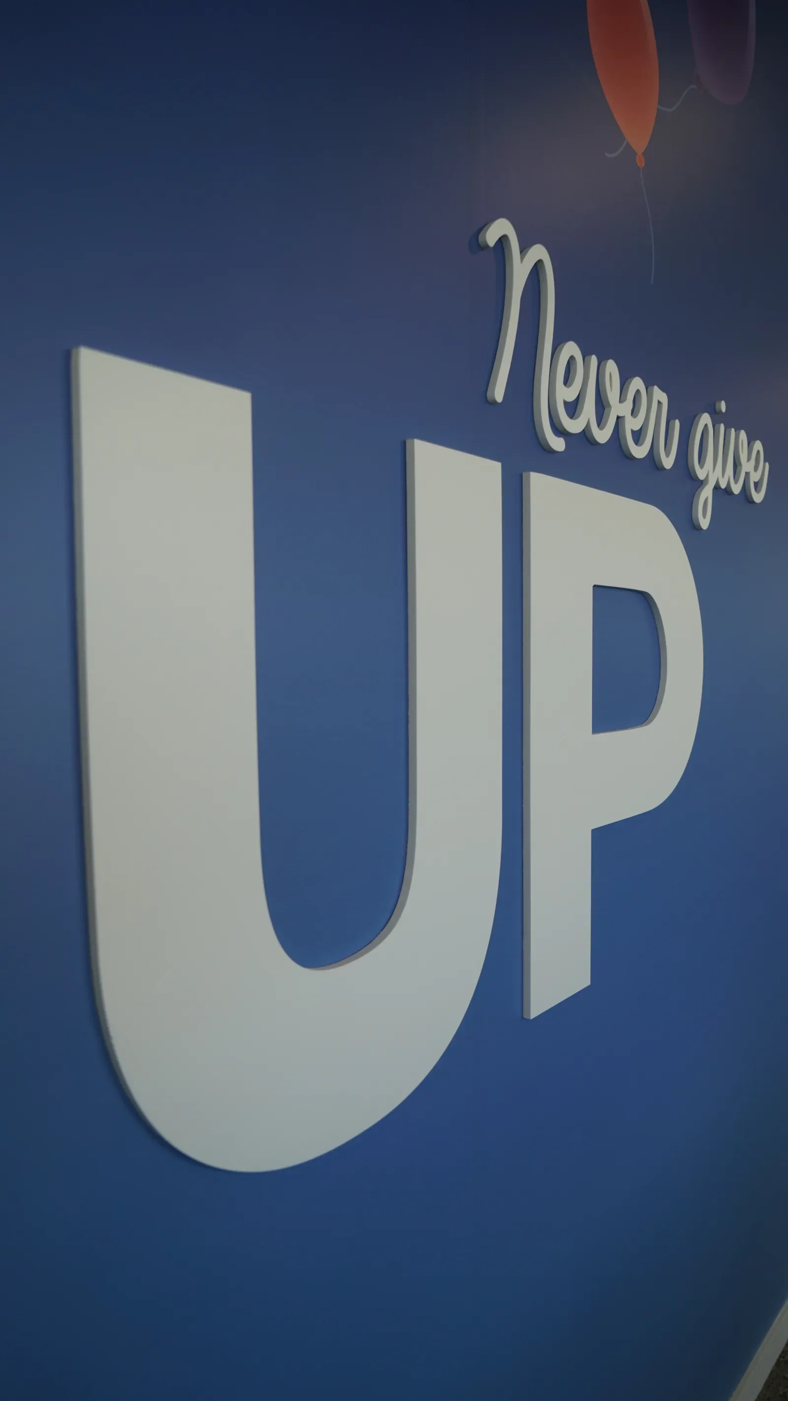 Grand U blanc en relief et mention Never give up sur un mur bleu