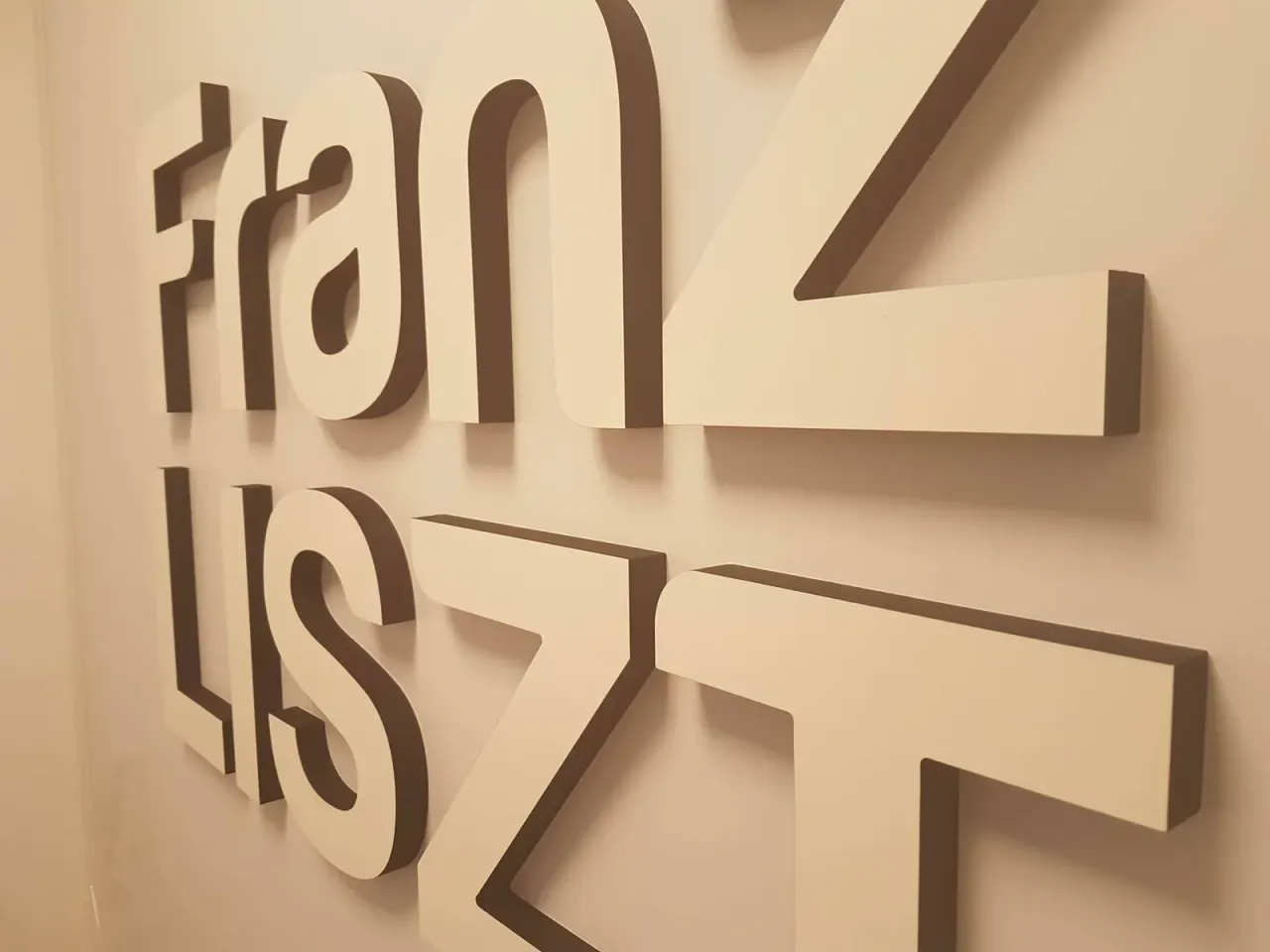 Nom de salle de réunion Franz Liszt en lettres PVC laquées blanches sur mur beige