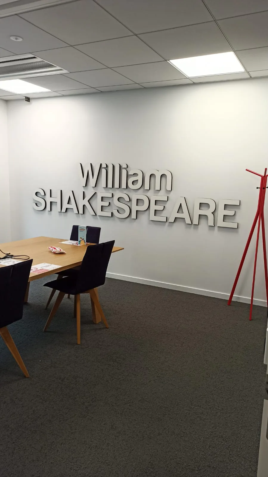 Nom de salle de réunion William Shakespeare en lettres grises en relief sur mur blanc