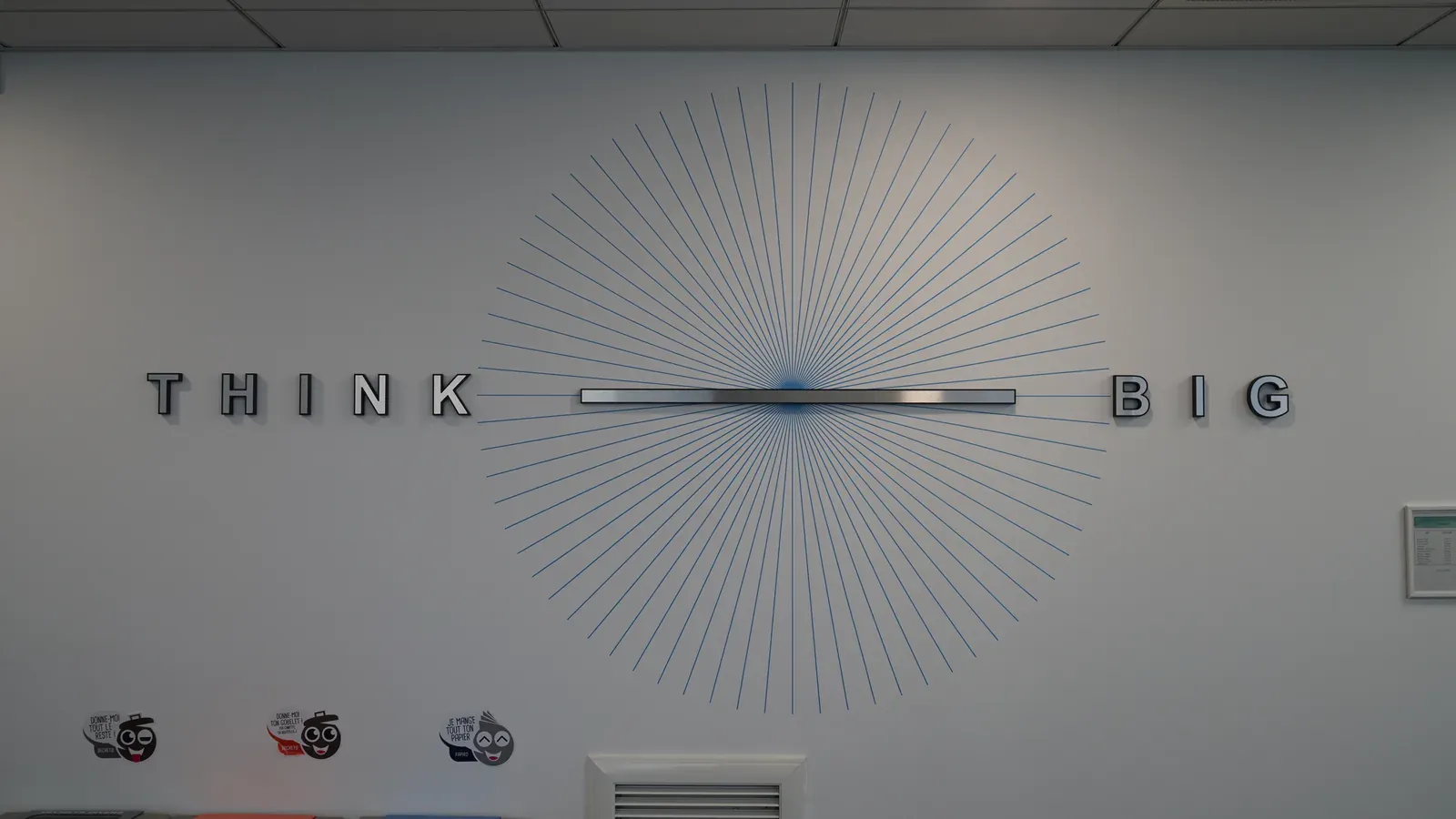Mots THINK et BIG de part et d'autre d'une horloge, sur un soleil de lignes graphiques