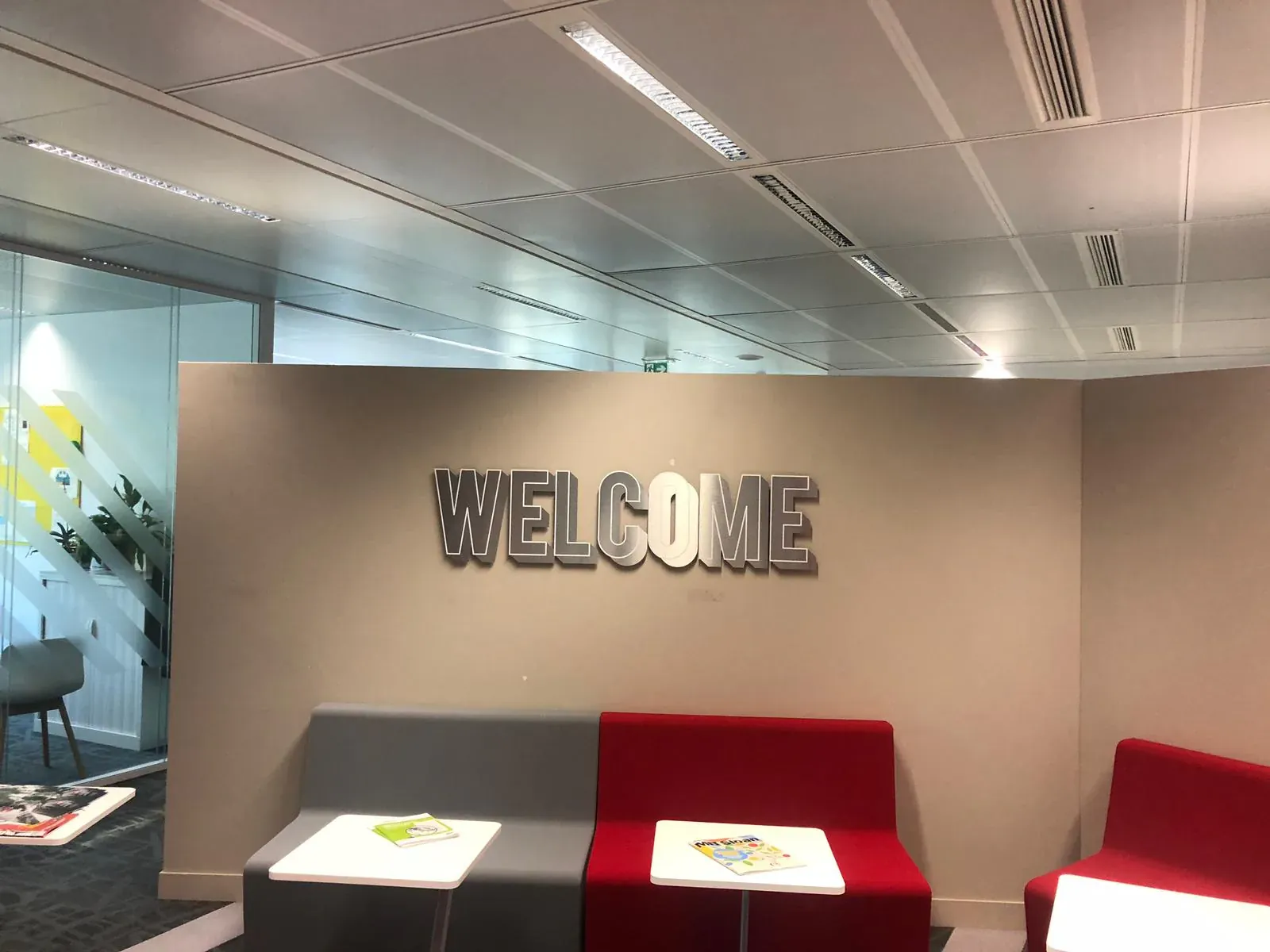 Mot WELCOME en lettres grises en relief au-dessus d'un espace d'accueil