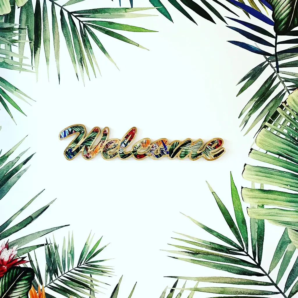 Mot Welcome en lettres décorées entouré de feuillages tropicaux