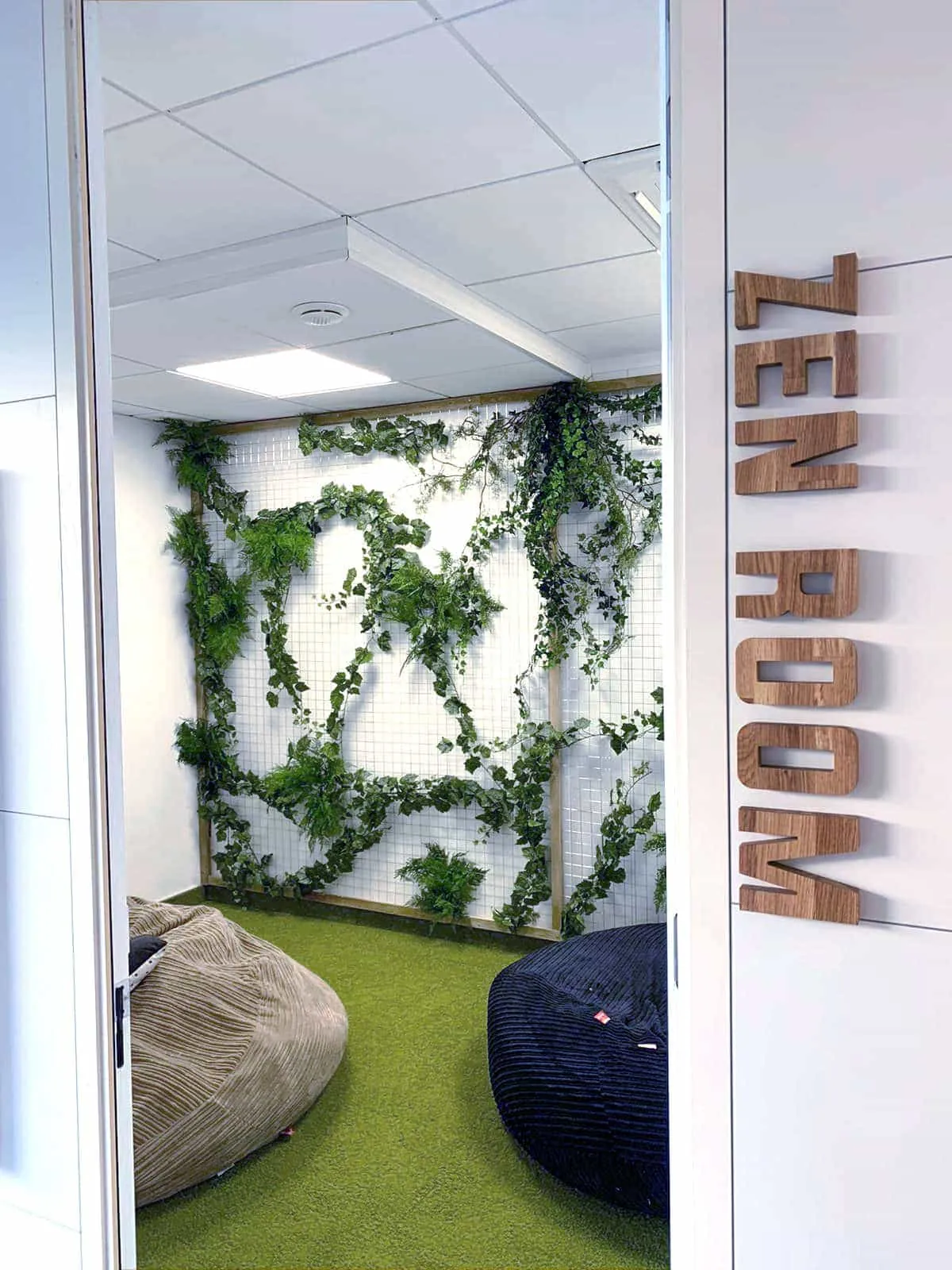 Mots ZEN ROOM en lettres de bois posées à la verticale à l'entrée d'une salle garnie de végétal